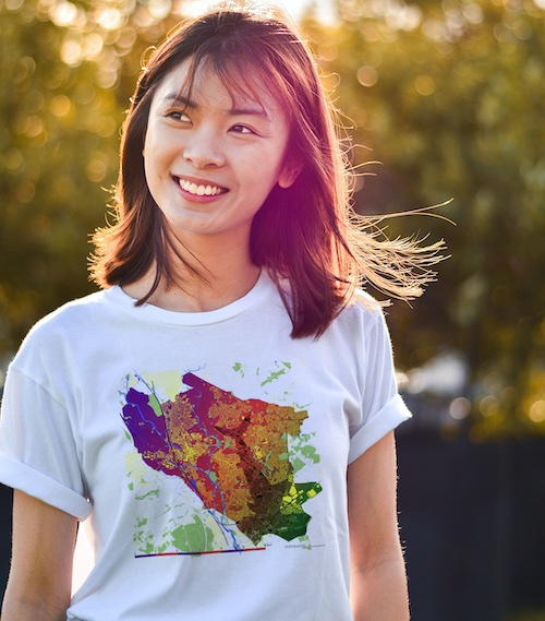 Woman wearing a white tshirt with a map of Oxford including a shark sticking out of a suburban house roof.
